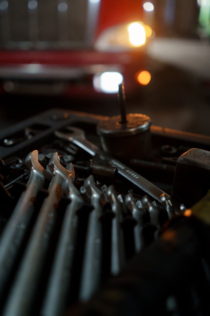 Close-up of mechanic's tools with classic car in the background, lit for night work ambiance.
