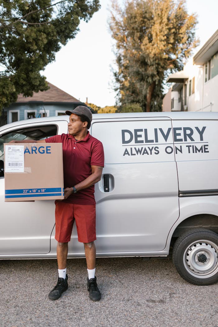 A deliveryman in uniform holding a large package by a delivery van, symbolizing efficient service.